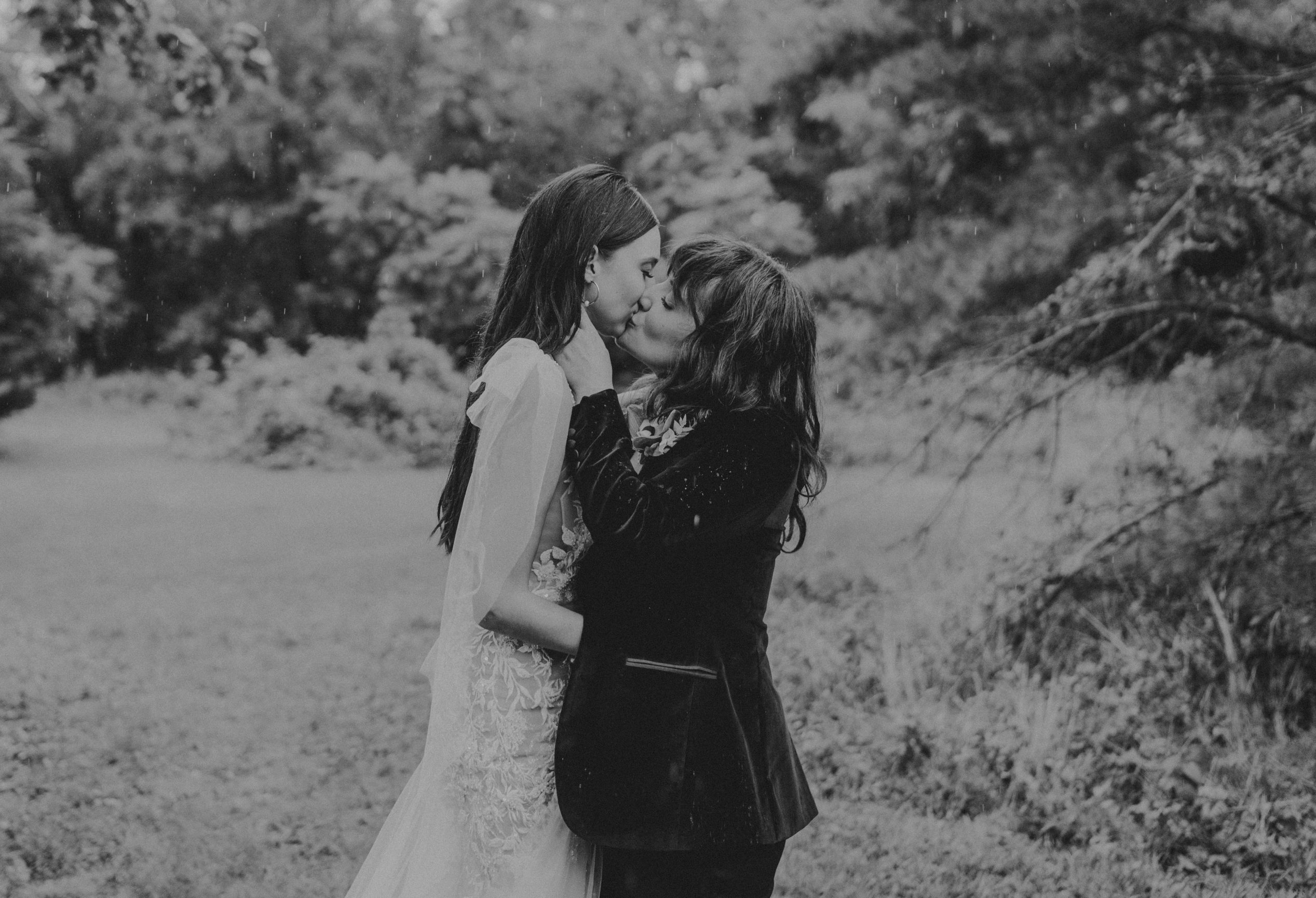 A couple kisses in the rain at a private estate wedding