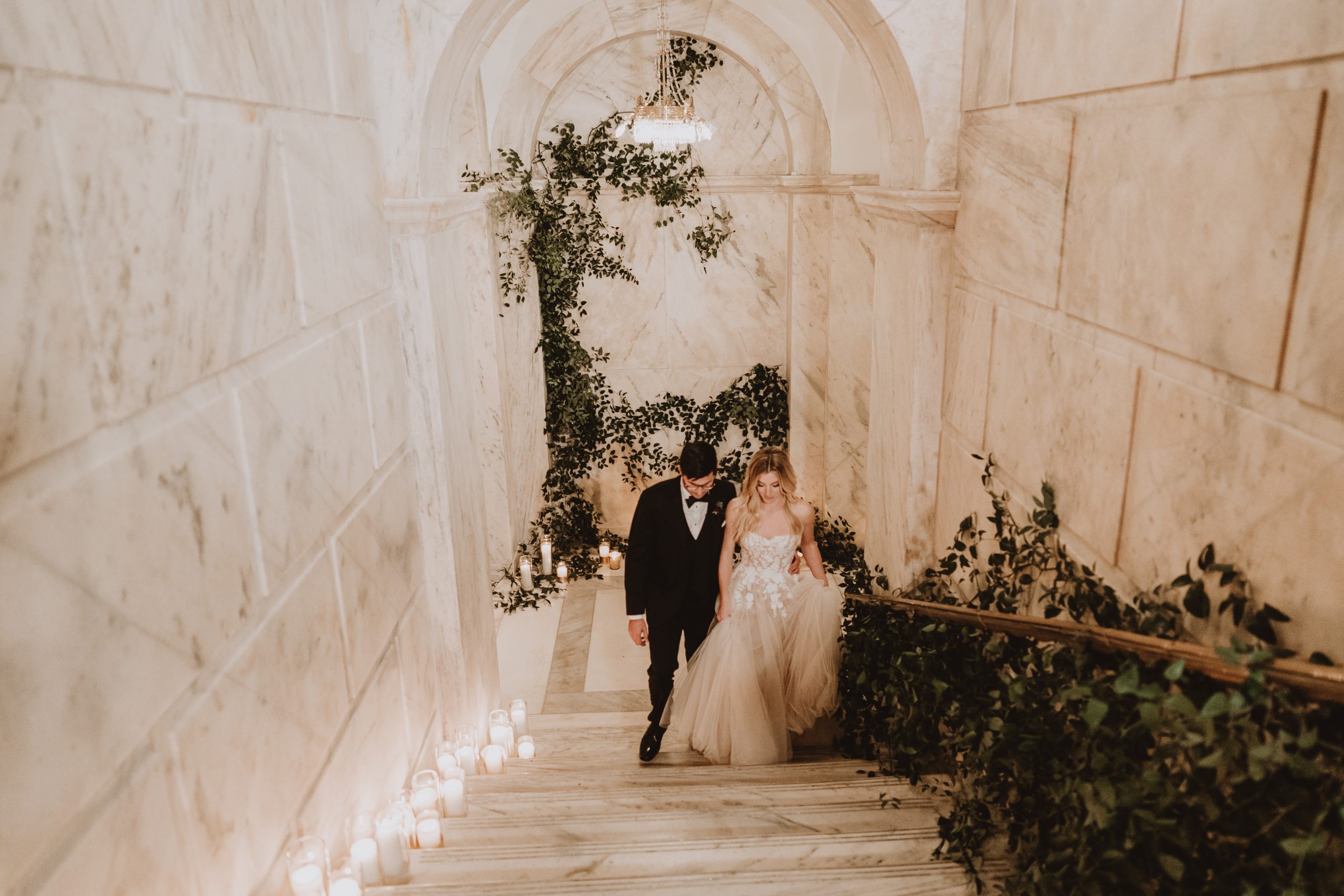 A newlywed couple descending an arched stone staircase