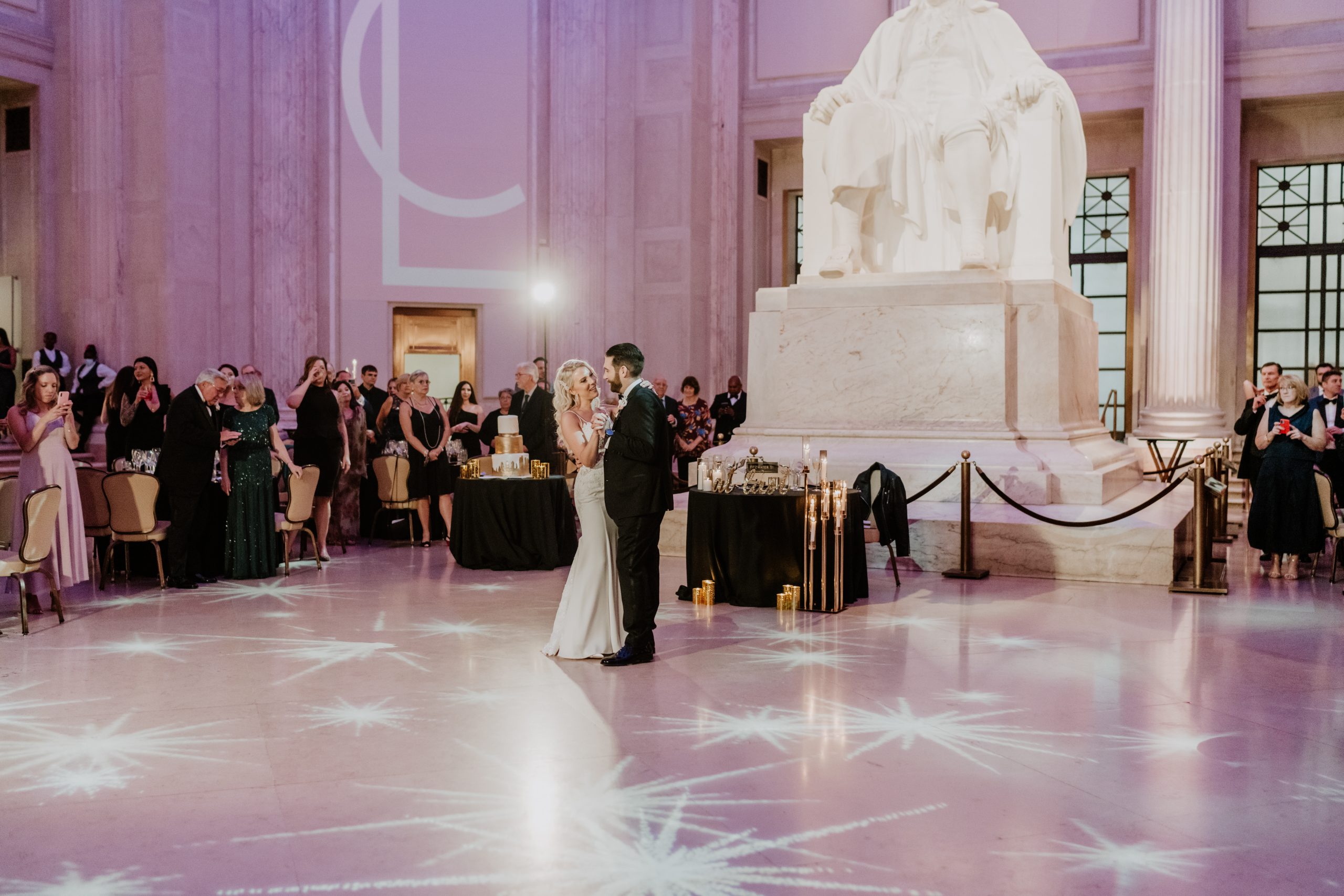 A newlywed couple dancing beneath the Benjamin Franklin Memorial at the Franklin Institute