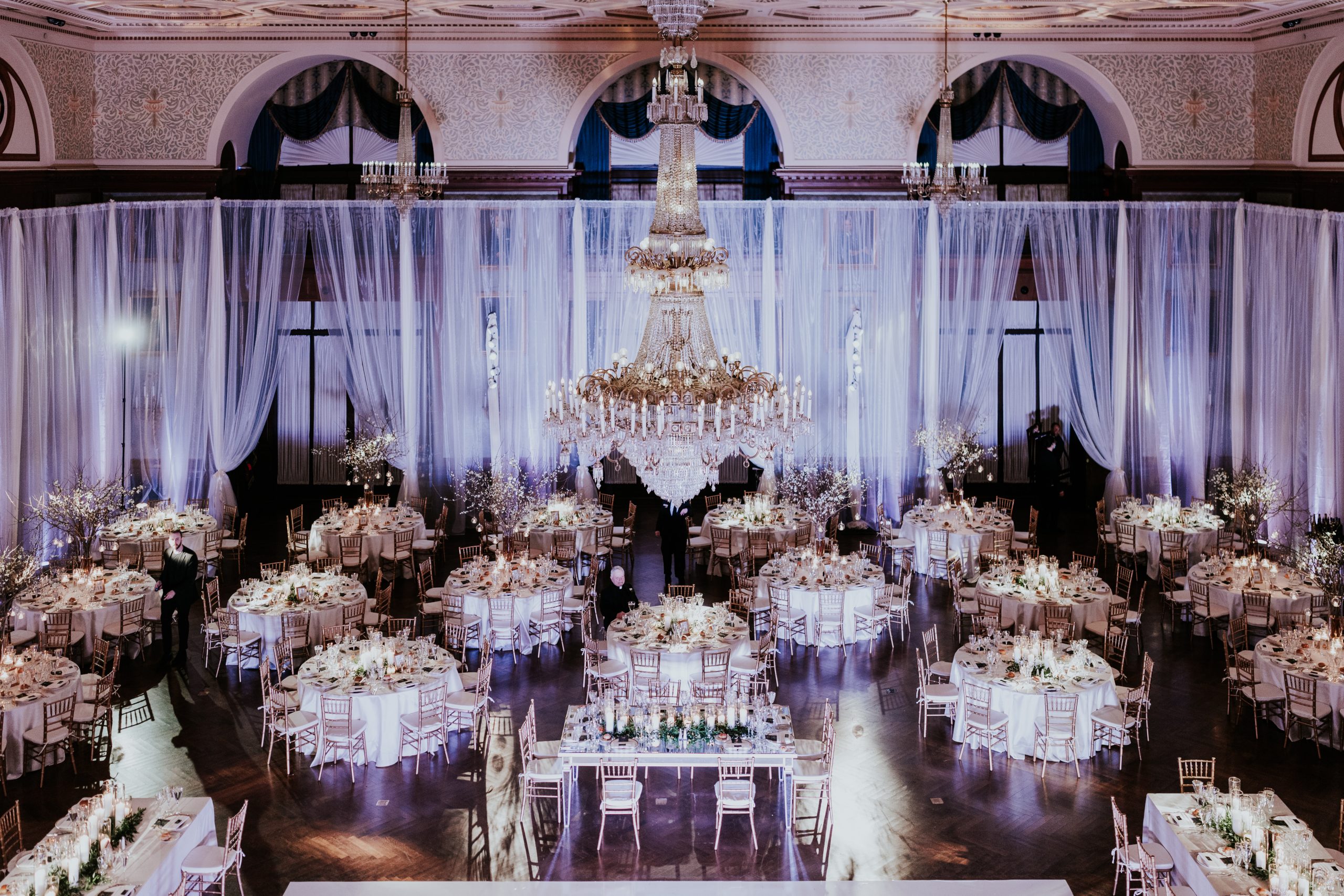 A chandelier-lit Union League ballroom prepared for a wedding reception