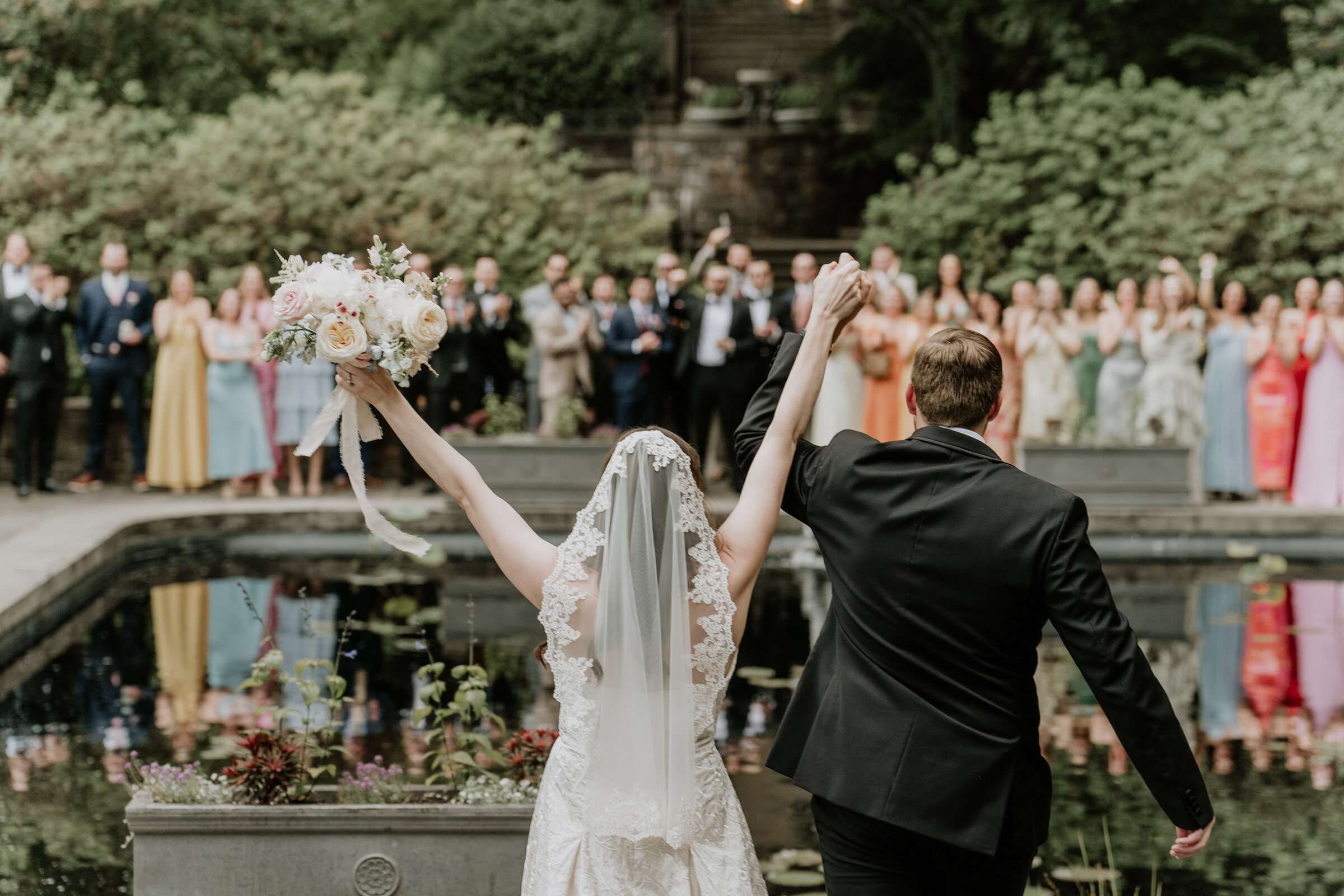 Kath and Luke raise their hands as wedding guests cheer at Winterthur