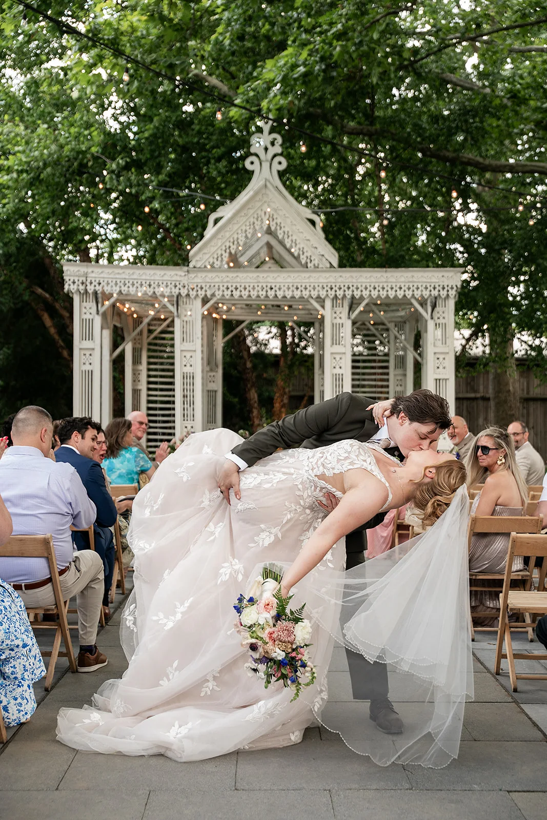 A newly married couple sharing a kiss as their Terrain at Styer's guests cheer