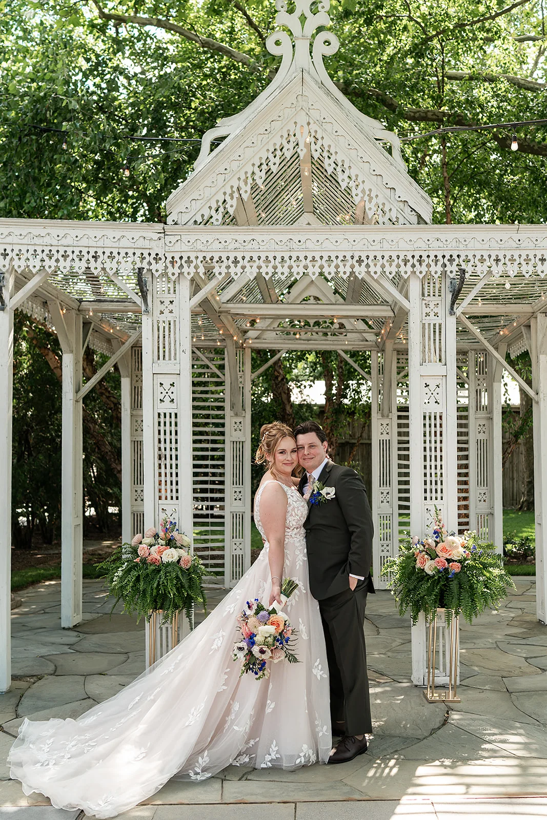 A couple photographed beneath the white Wedding Temple at Terrain at Styer's